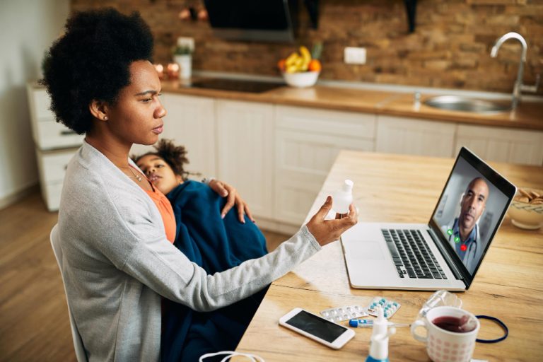 african-american-mother-having-video-call-with-pediatrician-while-holding-ill-daughter-her-lap (1)